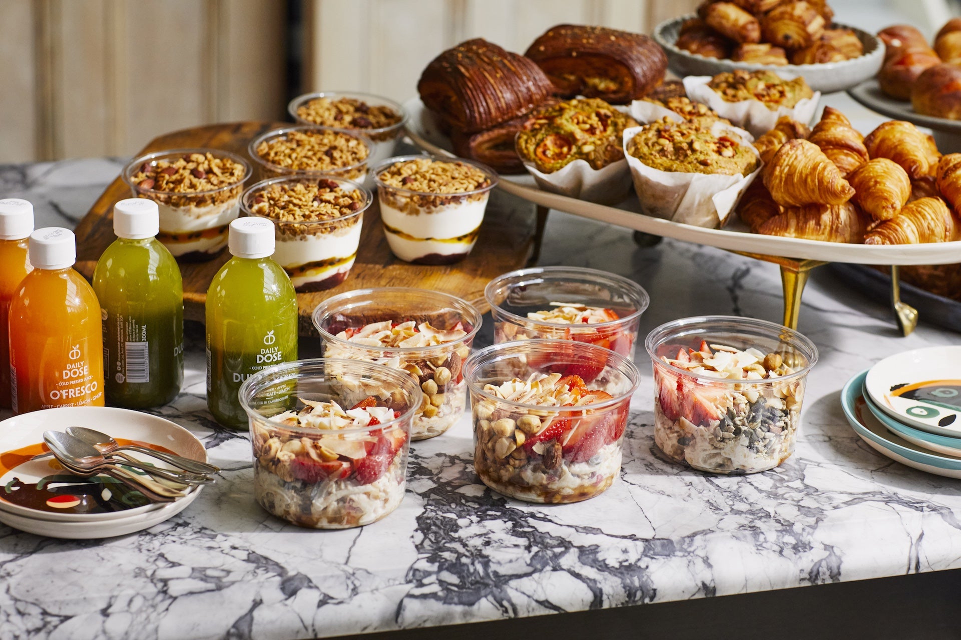 A breakfast display: juices, bircher muesli, yoghurt and granola pots and platter with morning pastries.