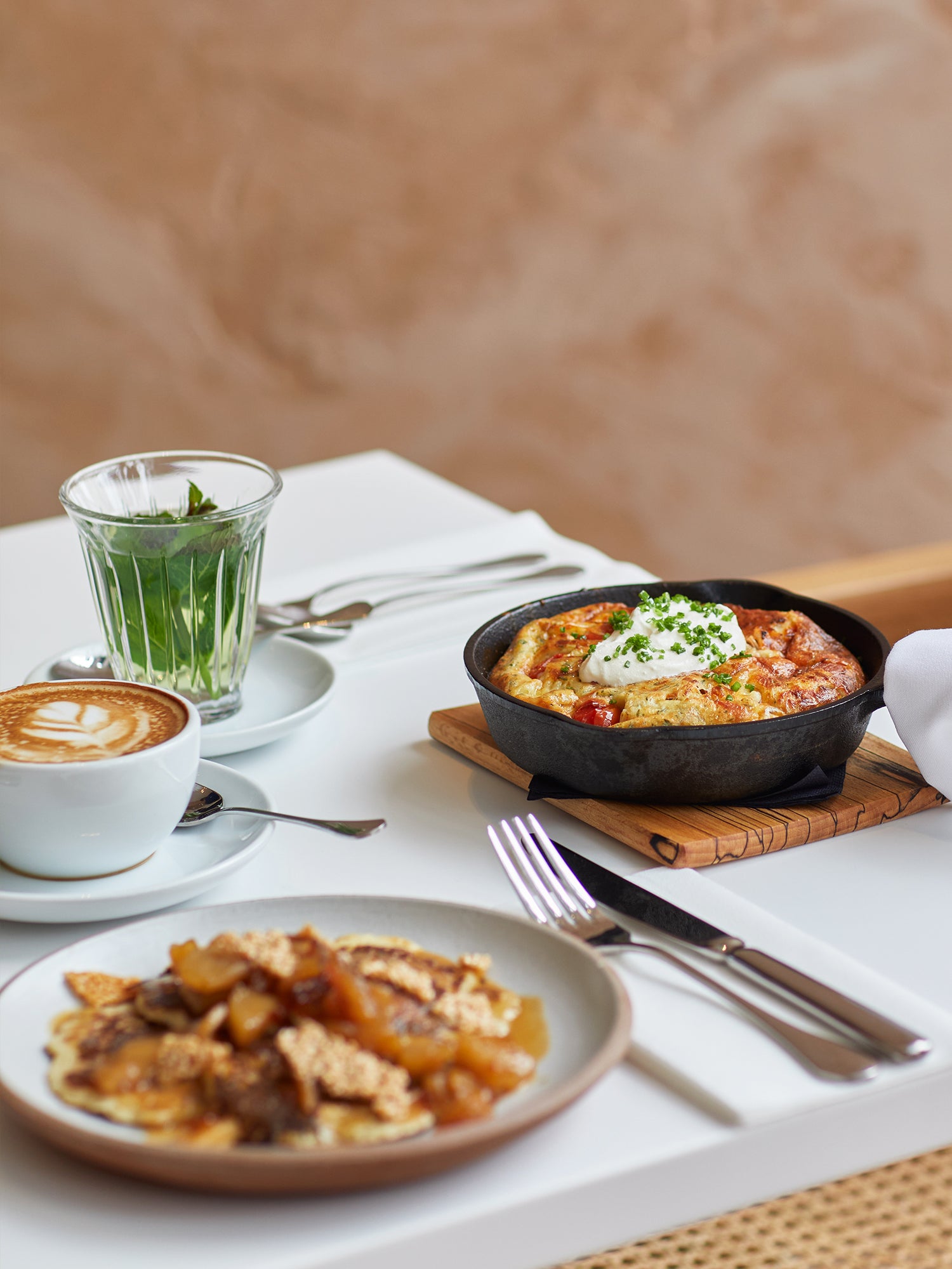 Dutch baby pancake with cherry tomatoes and sour cream, apple pancakes; fresh mint tea and flat white.