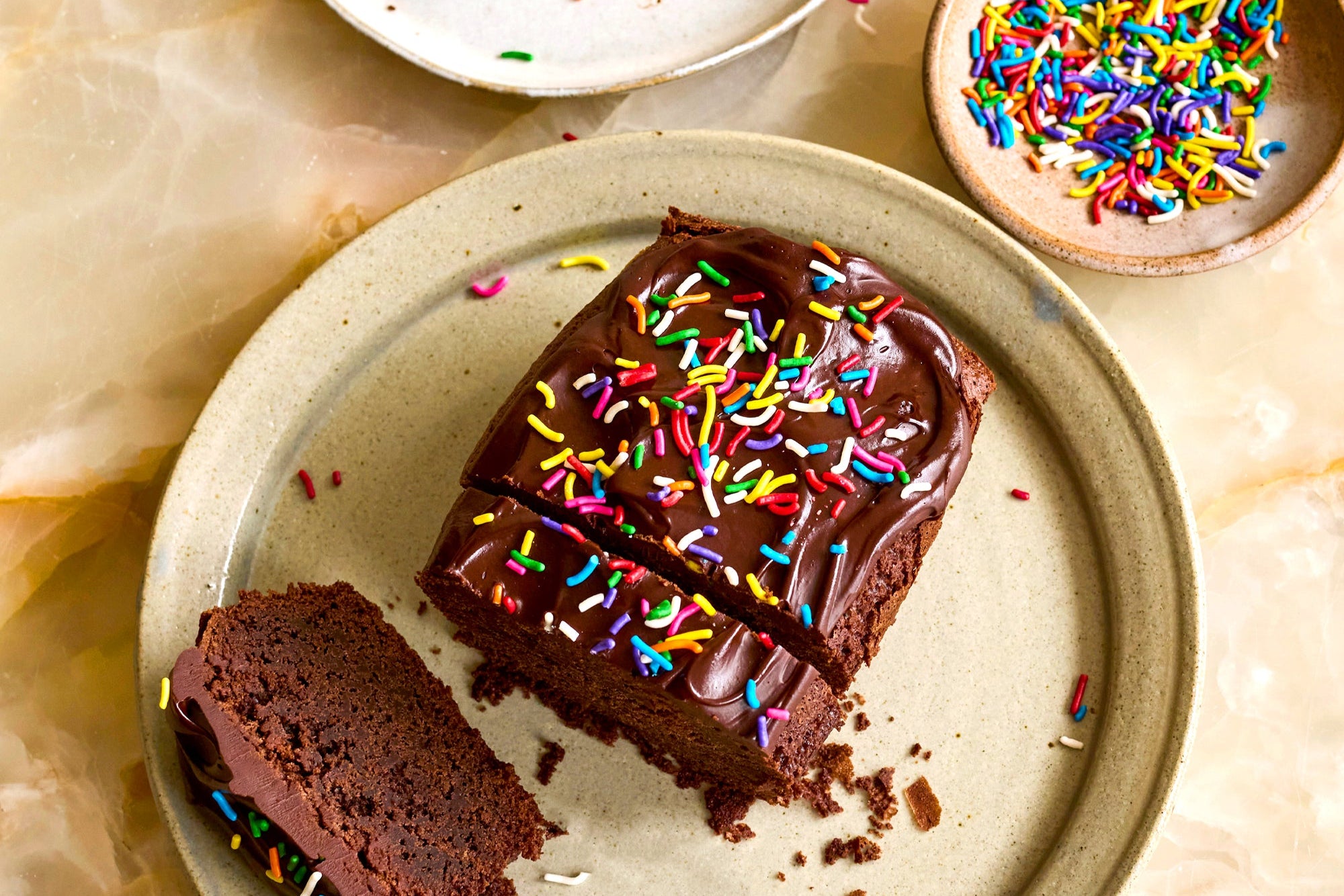 Chocolate cake with colorful sprinkles on a plate with a marble background