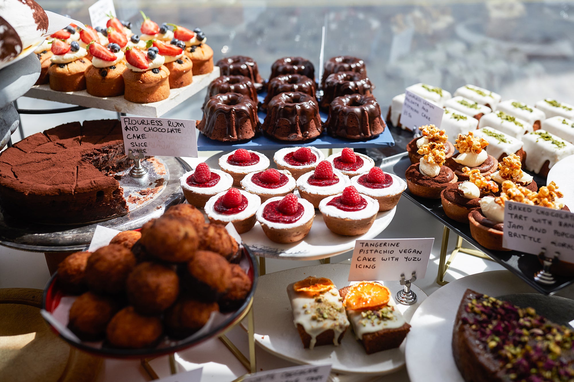 Display of cakes and pastries: cheesecake tarts, chocolate cake, macaroons, tangerine cakes, chocolate tarts etc. 