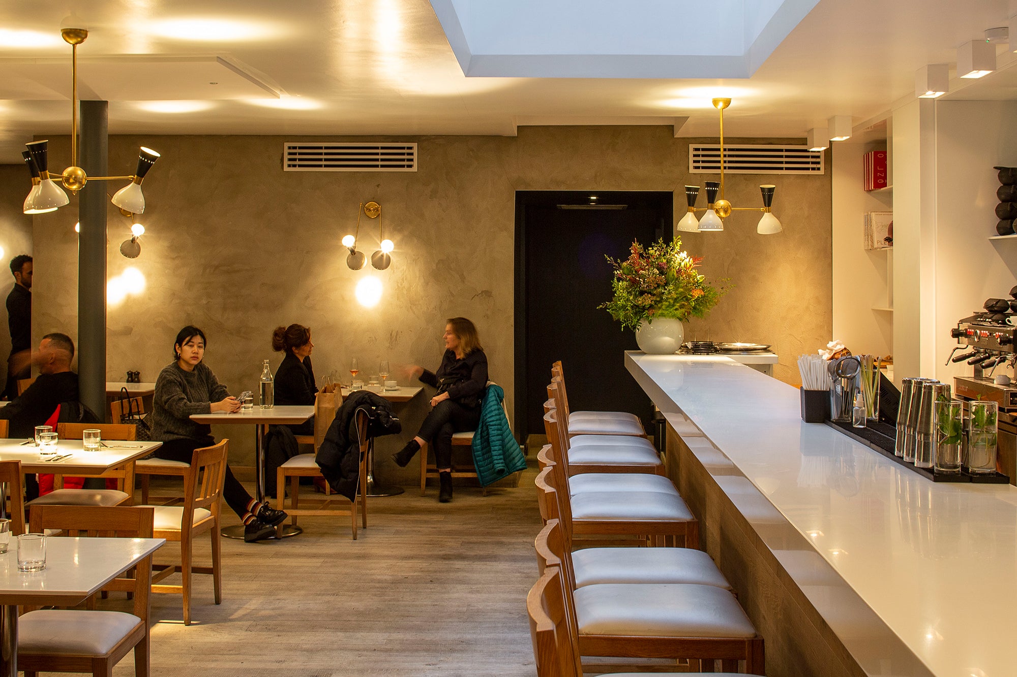 Dimly lit restaurant interior: tables with guests, bar counter on the right